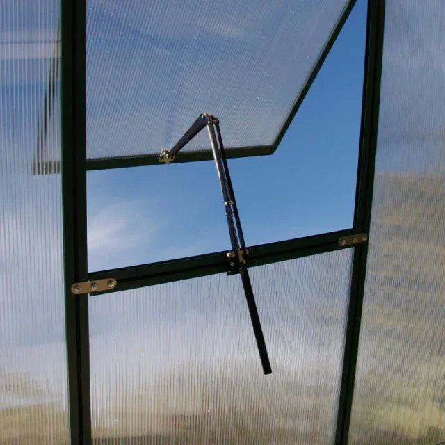 Open roof vent window with black metal arm against blue sky, greenhouse polycarbonate panels